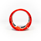 Flat surfaced resin cuff bracelet cast in a 60s inspired abstract pattern of orange, black and white resin. One edge is inlaid with black and white polka dots.
