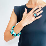 Model wearing multiple pieces from the Abstract Pop collection. It includes the teal Abstract pop cuff, the Teal Abstract Pop Disc bracelet and one-of-a-kind abstract statement ring.