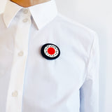 The oval abstract statement brooch worn on a white shirt by model.