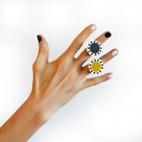 2 of the statement abstract rings worn on model's hand. One is black and white, the other is cast in lime green, black and white resin.