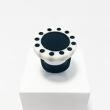 Large circular statement ring handmade from resin. The top is a circle cast in white resin with a black centre, which is surrounded with black polka dots. It is fitted to a black resin blank. 