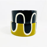 2 sixties patterned large bangles, one in black and white resin, the other in mustard, displayed on top of each other