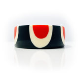 Close-up shot of the abstract pop cuff, showing the petal-shaped pattern inlaid in black, white and orange resin.