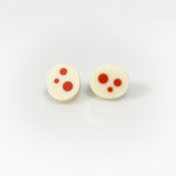 Oval shaped resin sud earrings cast in white and inlaid with orange polka dots. Fitted wit silver pins and disc plastic backs.