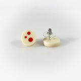 Oval shaped resin sud earrings cast in white and inlaid with orange polka dots. Fitted wit silver pins and disc plastic backs.