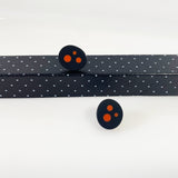 Oval shaped resin sud earrings cast in black and inlaid with orange polka dots. Fitted wit silver pins and disc plastic backs.