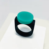 black resin finger ring fitted with a minimalist teal blue disc