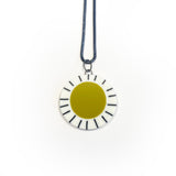 Large circle resin pendant cast with a mustard green centre and a white border, which is inlaid with black stripes. Hung on oxidised silver chunky snake chain.