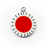 Large circle resin pendant cast with a orange centre and a white border, which is inlaid with black stripes.