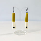 Minimalist chopstick shaped earrings cast in olive and white resin, inlaid with a black dot. Fitted with oxidised silver hooks.