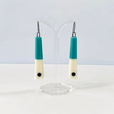 minimalist chopstick shaped earrings cast in teal and white resin, inlaid with a black dot. Fitted with oxidised silver hooks.