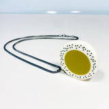 Oversized disc pendant cast in olive green and white resin, and inlaid with black polka dots. Hung on chunky oxidised silver chain.