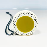 Oversized disc pendant cast in olive green and white resin, and inlaid with black polka dots. Hung on chunky oxidised silver chain.