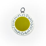 Oversized disc pendant cast in olive green and white resin, and inlaid with black polka dots.