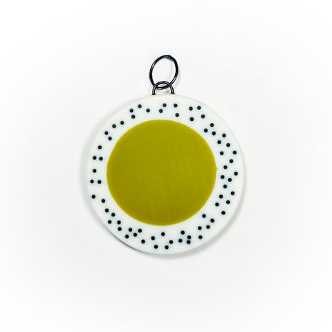 Oversized disc pendant cast in olive green and white resin, and inlaid with black polka dots.