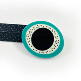 Sculptural oval shaped statement brooch cast in teal, white and black resin, inlaid with black dots.