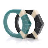 2 Art Deco resin bracelets standing, one in teal blue, the other in black, both  inlaid with Sun Ray style pattern in ivory white.