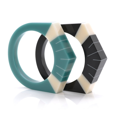 2 Art Deco resin bracelets standing, one in teal blue, the other in black, both  inlaid with Sun Ray style pattern in ivory white.