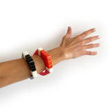 2 Art Deco resin bracelets, one black, one tangerine, worn by model's arm