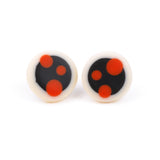Nabu circular stud earrings, handmade in white resin with a black centre, decorated with bright orange polka dots. Fitted with silver pins and comfy plastic and silver backs.
