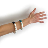 Minimalist statement resin bracelets cast in teal blue and black against ivory white