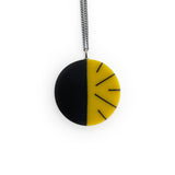 Lime yellow and black handmade resin pendant, cast in a circular shape and inlaid with a minimalist stripy design.