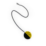 Yellow and black handmade resin pendant, cast in a circle shape and ornate with the minimalist Lunula design. On long oxidised silver chain.