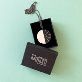 Black and white modernist Lunula pendant presented in Tiki gift box.