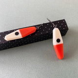 asymmetrical long diamond shaped earrings in a minimalist design of orange, black and white resin. Hung on oxidised sterling silver.