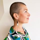 Minimalist chopstick shaped earrings modelled. They are cast in black and white resin, inlaid with a black dot. Fitted with oxidised silver hooks.