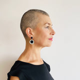 Black and white circle shaped resin dangle earrings worn by model