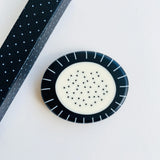 Large pebble shaped resin brooch cast in a black and white pattern of stripes and dots.  Displayed on white background.