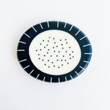 Large pebble shaped resin brooch cast in a black and white pattern of stripes and dots.  Displayed on white background.