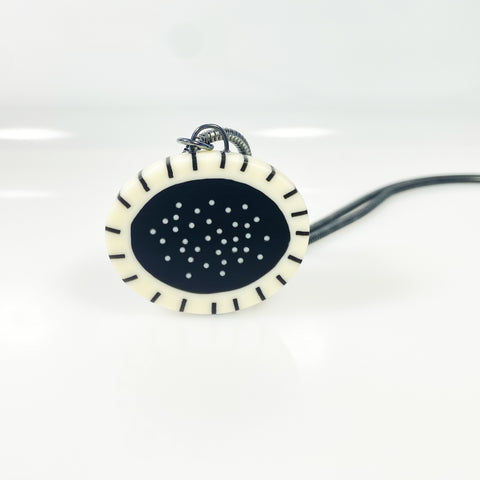 Monochrome  oval shaped resin pendant inlaid with polka dots and stripes. Fitted with an oxidised silver snake chain.