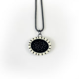 Monochrome  oval shaped resin pendant inlaid with polka dots and stripes. Fitted with an oxidised silver snake chain.