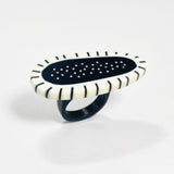 an abstract shaped chunky statement ring cast in black and white resin, inlaid with stripes and polka dots