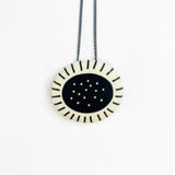 Necklace with a round pendant featuring a black center and white rim on a white background