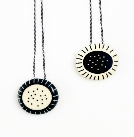 Two necklaces with circular pendants on a white background