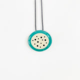 Necklace with a turquoise pendant featuring black dots on a white background
