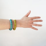 Two Lunula modernist resin bracelets worn by model. One is handmade from turquoise and white resin, the other in moss green and ivory. They are beautiful handmade statement bracelets, extremely tactile and lightweight. They also make a lovely sound, whilst clicking against each other.