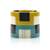 2 geometric resin bracelet cuffs, one in mustard, the other in teal, both inlaid with black and white stripes