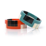 2 geometric resin bracelet cuffs, one in orange, the other in teal, both inlaid with black and white stripes