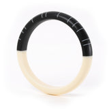 The minimalist Lunula bracelet, hand cast in resin and sanded to a soft tactile finish. The modernist design consists of one half cast in plain ivory white, the other in jet black, inlaid with contrasting white lines.