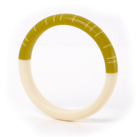 The Lunula modernist bracelet, hand cast in resin and  sanded to a smooth tactile finish. One side is cast in plain creamy white, the other in chartreuse green and inlaid with irregular white lines.
