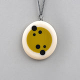handmade resin oval pendants cast in lime green and white resin, inlaid with black polka dots, fitted on oxidised sterling silver chain