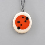 orange and white pebble shaped pendants, inlaid with black polka dots