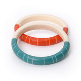 Two colourful geometric Lunula slim bracelets, handmade from resin. One is cast in teal and white resin, the other in paprika orange and white. Each bracelet is hand cast in 2 halves, one in ivory white, the other in opaque colour, inlaid with contrasting white lines. Hand sanded to a smooth tactile finish, they are extremely lightweight and very pleasant to wear.