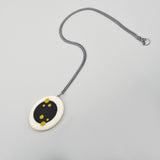 Long Nabu reversible pendant, handmade from black and white resin, ornate with mustard green polka dots. The pendant is extremely smooth, tactile and lightweight. The other side is plain and dotless. The pendant hangs on a 60cm Sterling silver oxidised chain.