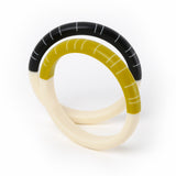 Two handmade resin geometric Lunula bracelets, displaying the beautiful half-half modernist design. One is cast in black and white, the other in mustard green and white.