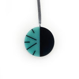 Teal blue and black resin circular pendant, cast in a stripy modernist design. On long oxidised Sterling silver chain.